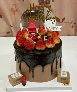 เค้กวันเกิดช็อกโกแลตตกแต่งด้วยสตรอว์เบอร์รีสดและของตกแต่งคำว่า Happy Birthday บนยอดเค้ก.