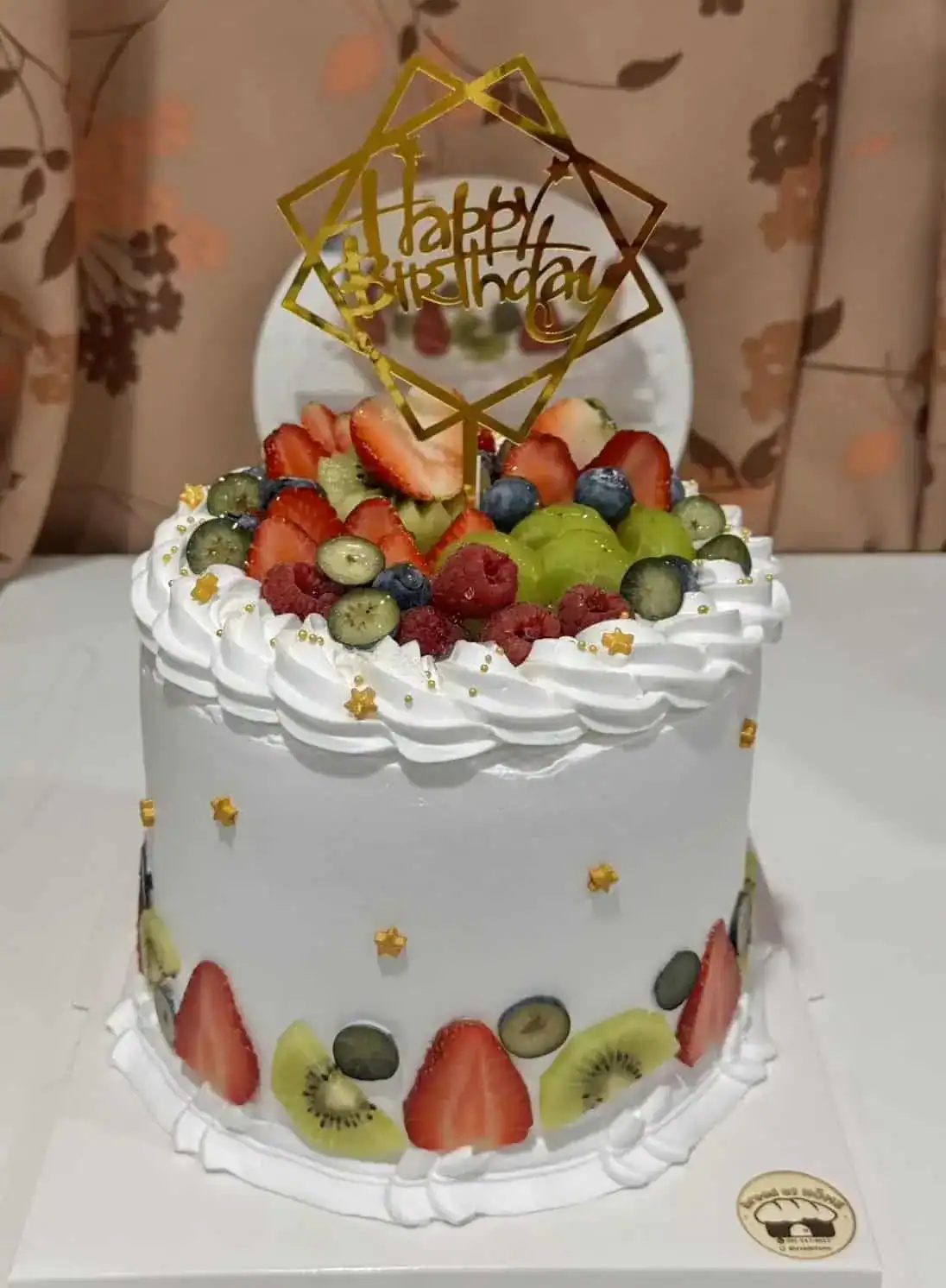 เค้กวันเกิดผลไม้สดพร้อมคำว่า Happy Birthday บนยอดเค้ก สร้างความสุขในโอกาสพิเศษ.