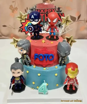 เค้กวันเกิดสองชั้นตกแต่งด้วยตัวการ์ตูนซุปเปอร์ฮีโร่จาก Marvel และ DC พร้อมของตกแต่งทองคำและดาวสีทอง.