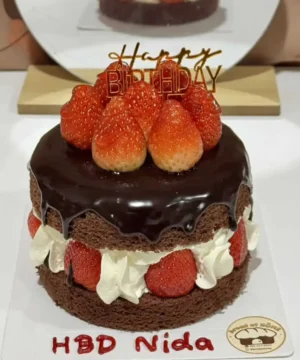 เค้กวันเกิดช็อกโกแลตตกแต่งด้วยสตรอว์เบอร์รี่และเทียนคำว่า