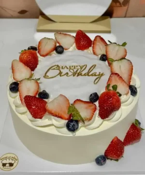 เค้กวันเกิดผลไม้สดตกแต่งด้วยสตรอเบอร์รี่ บลูเบอร์รี่ และครีมสด พร้อมคำว่า Happy Birthday.