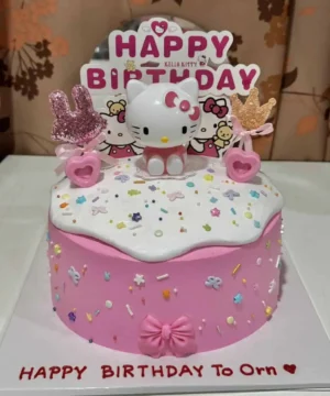 เค้กวันเกิดคิตตี้สีชมพูพร้อมตกแต่งด้วยตัวการ์ตูน Hello Kitty และของตกแต่งน่ารัก เช่น ร็อคกี้และหัวใจ.