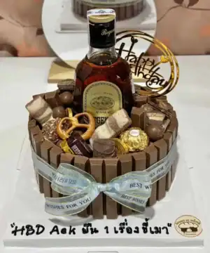 เค้กช็อกโกแลตตกแต่งด้วยช็อกโกแลตและขนมหวาน พร้อมขวดเหล้ารัมและการ์ดอวยพรวันเกิด.