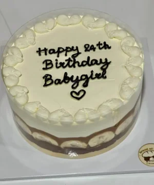 เค้กวันเกิดสีขาวพร้อมข้อความ Happy 2th Birthday Baby girl และตกแต่งด้วยครีมและช็อกโกแลต.