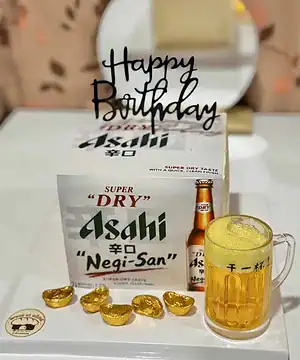 แก้วเบียร์ Asahi เนกิซัง พร้อมกล่องและช็อกโกแลตทองคำในงานปาร์ตี้วันเกิด.