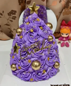 เค้กต้นคริสต์มาสสีม่วงประดับดาวทองและลูกบอลทอง สวยงามสำหรับฉลองเทศกาลคริสต์มาสและวันเกิดในช่วงฤดูหนาว.