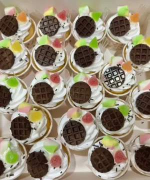 หวานกล่องของคัพเค้กที่ตกแต่งด้วยช็อกโกแลตและลูกกวาดสีสันสดใส พร้อมเนื้อสัมผัสนุ่มนวลและรสชาติหวานอร่อย เติมเต็มความสุขในทุกคำ.