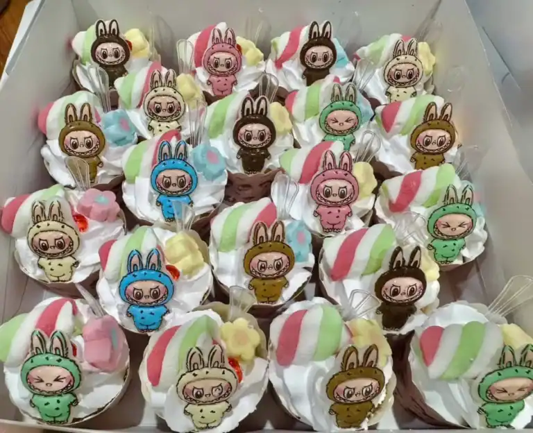 คัพเค้กลายการ์ตูนสุดน่ารักตกแต่งด้วยวิปครีมและช็อกโกแลต พร้อมตัวการ์ตูนลายคัพเค้กน่ารักในธีมสุดฮิต เหมาะสำหรับงานปาร์ตี้และของขวัญพิเศษ.