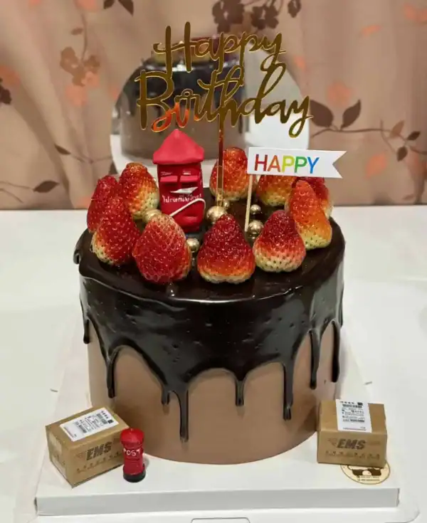 เค้กวันเกิดช็อกโกแลตตกแต่งด้วยสตรอว์เบอร์รีสดและของตกแต่งคำว่า Happy Birthday บนยอดเค้ก.