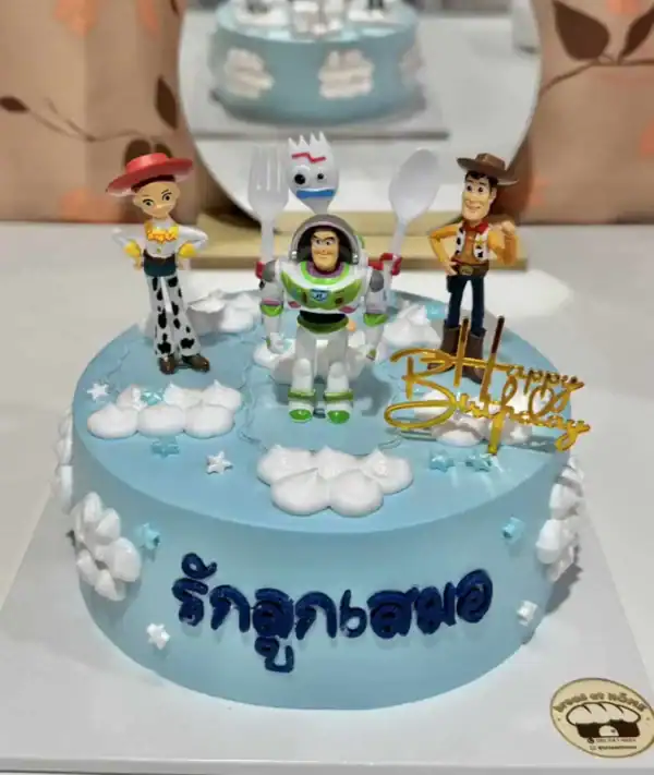 เค้กวันเกิดธีม Toy Story พร้อมตัวละคร Buzz Lightyear, Woody, Jessie และ Forky บนเค้กสีฟ้า พร้อมคำอวยพรและตกแต่งน่ารัก.