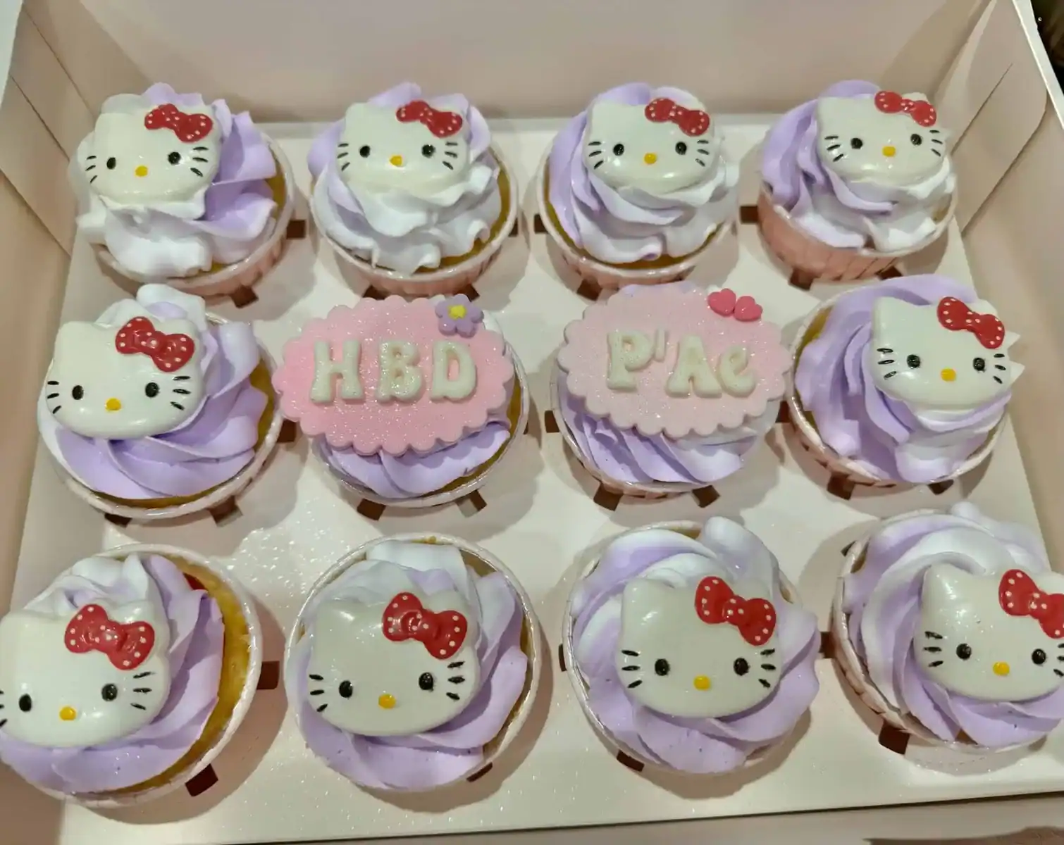 คัพเค้กคิตตี้ Hello Kitty สีชมพูและม่วง พร้อมตกแต่งด้วยครีมและลายคิตตี้น่ารัก เหมาะสำหรับงานปาร์ตี้และของขวัญสุดพิเศษ.