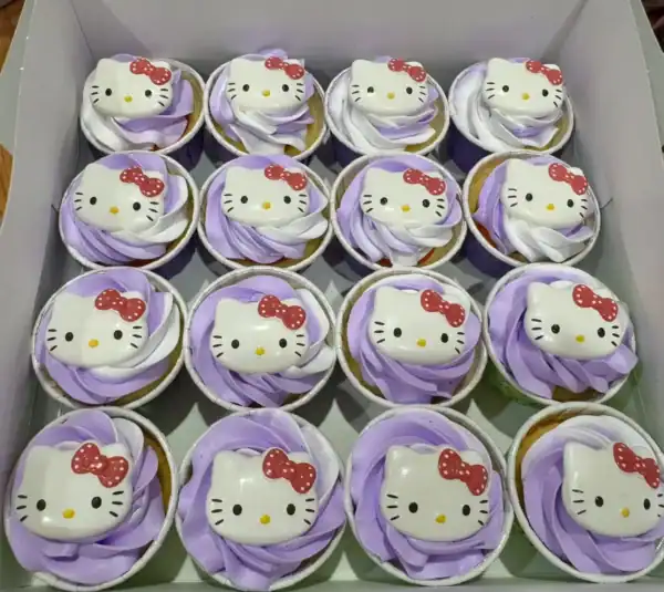 คัพเค้กคิตตี้ Hello Kitty สีขาวและม่วง พร้อมตกแต่งด้วยหน้าคิตตี้และโบว์แดง.