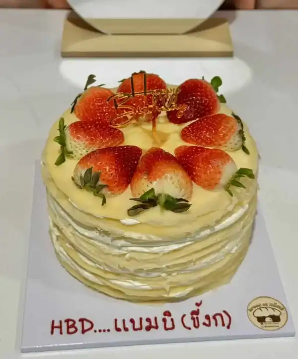 เค้กสตรอว์เบอร์รีชั้นสูงตกแต่งด้วยผลไม้สดและใบสะระแหน่ เหมาะสำหรับงานฉลองวันเกิดหรือโอกาสพิเศษ.