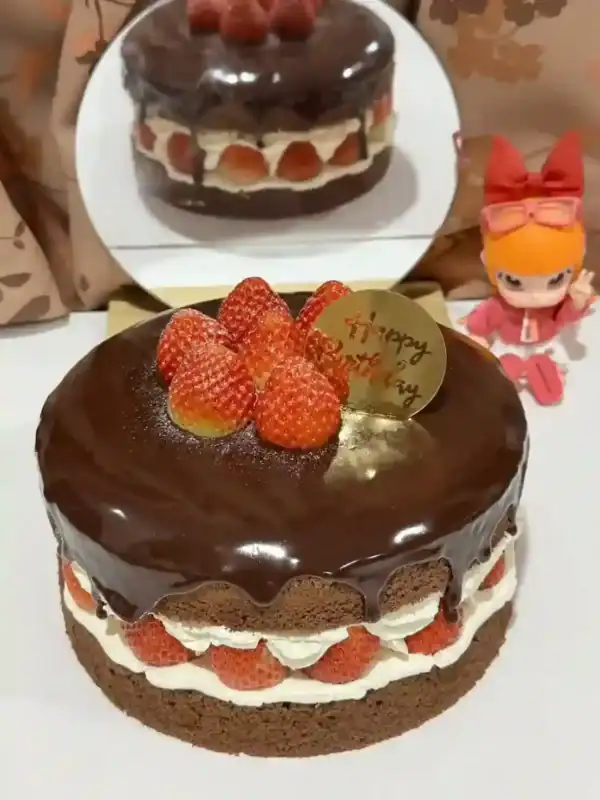 เค้กช็อกโกแลตสตรอเบอร์รี่สุดหรู พร้อมชั้นครีมและผลไม้สด ราดด้วยซอสช็อกโกแลตเข้มข้น เหมาะสำหรับงานพิเศษและคนรักของหวาน.