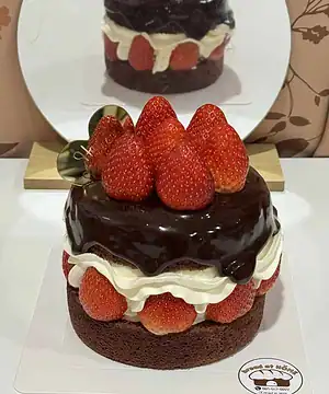 เค้กช็อกโกแลตสตรอเบอร์รี่เน้นความหวานและรสชาติเข้มข้น พร้อมผลสตรอเบอร์รี่สดบนหน้าเค้กและช็อกโกแลตเข้มข้น.