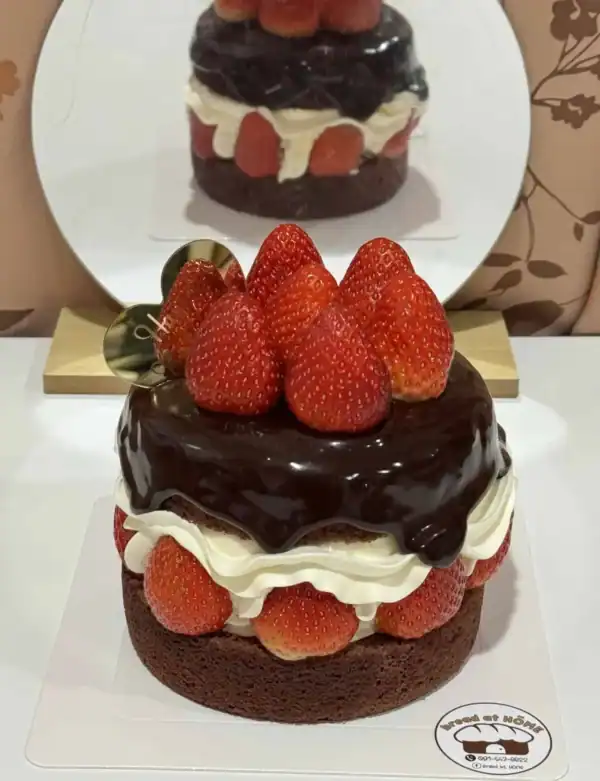 เค้กช็อกโกแลตสตรอเบอร์รี่เน้นความหวานและรสชาติเข้มข้น พร้อมผลสตรอเบอร์รี่สดบนหน้าเค้กและช็อกโกแลตเข้มข้น.