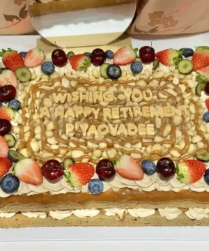 เค้กกาแฟคาราเมลแมคคาเดเมียตกแต่งด้วยผลไม้สดและครีมหวานอร่อย เหมาะสำหรับงานฉลองและเป็นของขวัญพิเศษ.