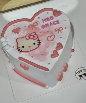 เค้กหัวใจตกแต่งลายคิตตี้สีชมพูและขาว พร้อมข้อความ HBD ORACE สำหรับฉลองวันเกิดสุดน่ารัก.
