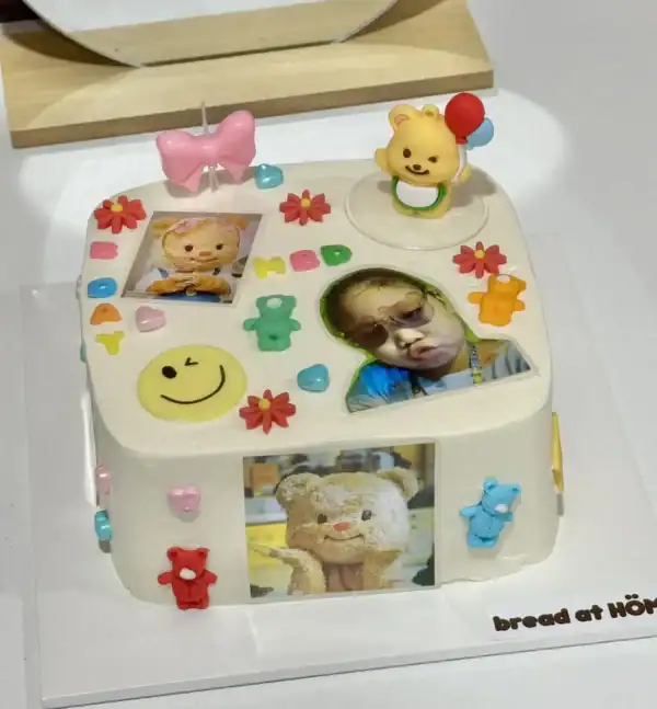 ภาพเค้กวันเกิดตกแต่งด้วยภาพถ่ายและของตกแต่งน่ารัก ตกแต่งด้วยลูกอม ดอกไม้ และตัวการ์ตูนสีสันสดใส สื่อถึงความสุขและความสนุกในโอกาสพิเศษสำหรับเด็ก ๆ.