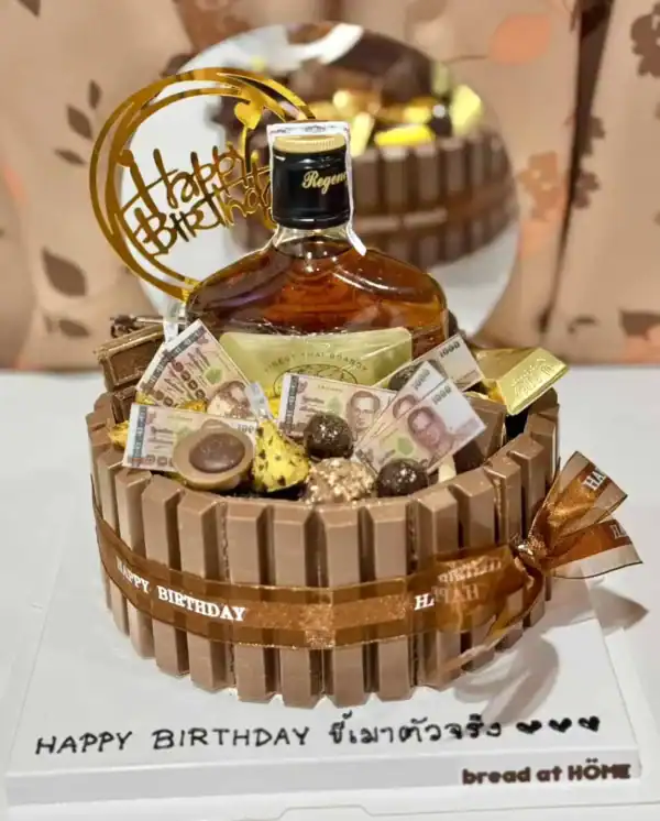 ดวงวิสกี้ในกล่องแก้วพร้อมของขวัญสุดหรู เลิร์ดทองคำ ริมฝีปากหวานช็อกโกแลตและช็อคโกแลตแท่งทองคำบนของเค้กวันเกิดหวานหรูสำหรับโอกาสพิเศษ.