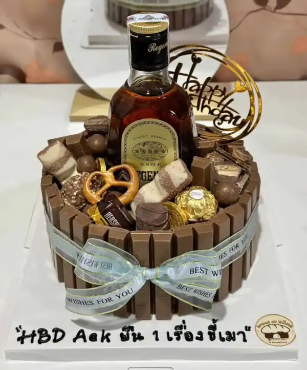 เค้กช็อกโกแลตตกแต่งด้วยช็อกโกแลตและขนมหวาน พร้อมขวดเหล้ารัมและการ์ดอวยพรวันเกิด.