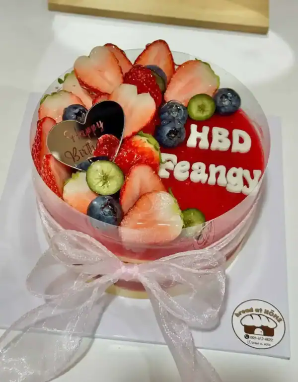 อาหารหวานเค้กผลไม้สด สตรอเบอรี่ บลูเบอรี่ และกีวี ตกแต่งอย่างสวยงามบนเค้กเนียนนุ่ม พร้อมคำอวยพรวันเกิด.