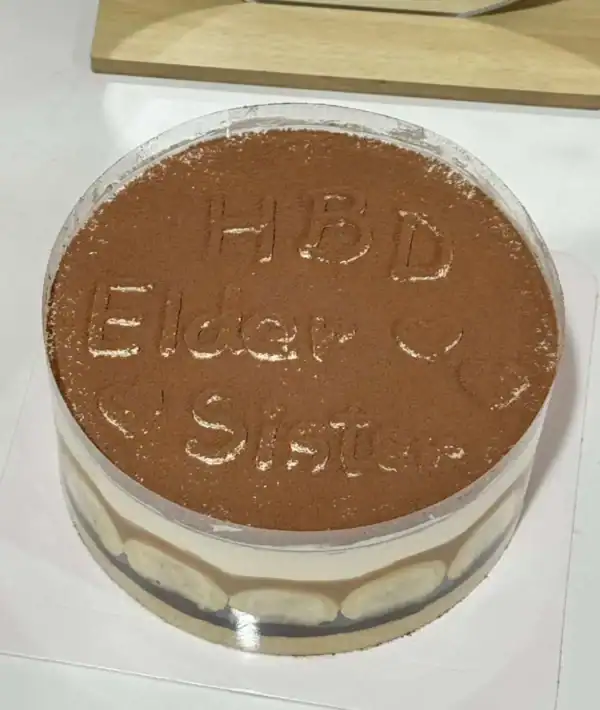 เค้กบานอฟฟี่พายช็อกโกแลตกล้วยหวาน พร้อมตกแต่งด้วยผงโกโก้และลายตัวอักษรบนหน้าเค้ก.