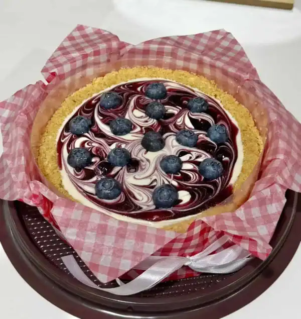 ชีสพายบลูเบอรี่สด พร้อมซอสบลูเบอรี่และครัสต์กรอบ เสิร์ฟบนจานสีดำ สร้างความน่ารับประทานและดึงดูดสายตา.