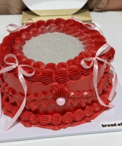 เค้กกลิตเตอร์สีแดงสดใส พร้อมตกแต่งด้วยริบบิ้นและเพชรประดับ สร้างความโดดเด่นในทุกงานฉลองและโอกาสพิเศษ.