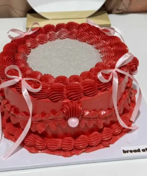 เค้กกลิตเตอร์สีแดงสดใส พร้อมตกแต่งด้วยริบบิ้นและเพชรประดับ สร้างความโดดเด่นในทุกงานฉลองและโอกาสพิเศษ.