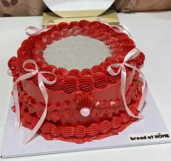 เค้กกลิตเตอร์สีแดงสดใส พร้อมตกแต่งด้วยริบบิ้นและเพชรประดับ สร้างความโดดเด่นในทุกงานฉลองและโอกาสพิเศษ.