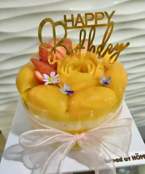 เค้กมะยงชิดสดหวานฉ่ำ เนื้อแน่น รสชาติเป็นเอกลักษณ์ พร้อมตกแต่งด้วยดอกไม้และคำอวยพรวันเกิด.