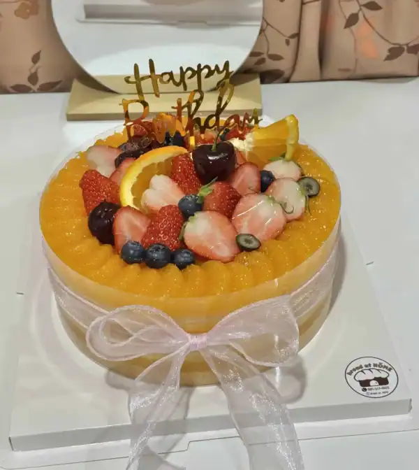 เค้กส้มหน้านิ่มพรีเมียม พร้อมผลไม้สดและซอสส้มคั้นสด เสิร์ฟในบรรยากาศอบอุ่นและหรูหรา เหมาะสำหรับโอกาสพิเศษและวันเกิด.