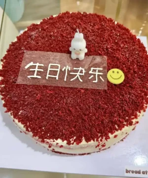 เค้กเรดเวลเวทเนื้อเนียนนุ่ม เคลือบด้วยผงโกโก้แดงสด พร้อมตกแต่งด้วยของตกแต่งน่ารักและข้อความในภาษาจีนบนหน้าเค้ก.