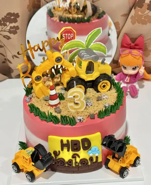 เค้กวันเกิดสำหรับเด็กตกแต่งด้วยรถแม็คโครสีเหลืองสดใส พร้อมของตกแต่งน่ารักและตัวเลข 3 สำหรับฉลองวันเกิดในธีมเครื่องจักรกลหนัก.
