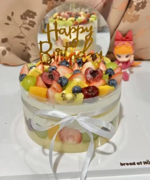 เค้กผลไม้สดรวมหน้าตาน่ารับประทาน ประดับด้วยผลไม้หลากหลายชนิดและคำว่า Happy Birthday บนยอดเค้ก สำหรับงานเลี้ยงวันเกิด.