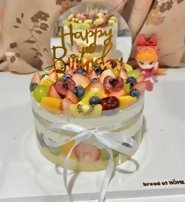 เค้กผลไม้สดรวมหน้าตาน่ารับประทาน ประดับด้วยผลไม้หลากหลายชนิดและคำว่า Happy Birthday บนยอดเค้ก สำหรับงานเลี้ยงวันเกิด.
