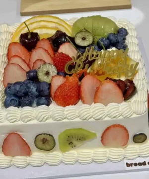 เค้กผลไม้สดรวมที่ตกแต่งด้วยผลไม้หลากหลาย เช่น สตรอเบอร์รี่ กีวี บลูเบอร์รี่ และแตงโม สร้างความสดชื่นและความสุขในทุกคำ.