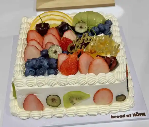 เค้กผลไม้สดรวมที่ตกแต่งด้วยผลไม้หลากหลาย เช่น สตรอเบอร์รี่ กีวี บลูเบอร์รี่ และแตงโม สร้างความสดชื่นและความสุขในทุกคำ.
