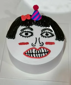 เส้นขนมปังตกแต่งเป็นใบหน้าและเค้กวันเกิดแบบสนุกสนาน ตกแต่งด้วยสีสันสดใสและหัวหมวกวันเกิดสำหรับงานเลี้ยงฉลองพิเศษ.