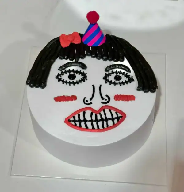 เส้นขนมปังตกแต่งเป็นใบหน้าและเค้กวันเกิดแบบสนุกสนาน ตกแต่งด้วยสีสันสดใสและหัวหมวกวันเกิดสำหรับงานเลี้ยงฉลองพิเศษ.