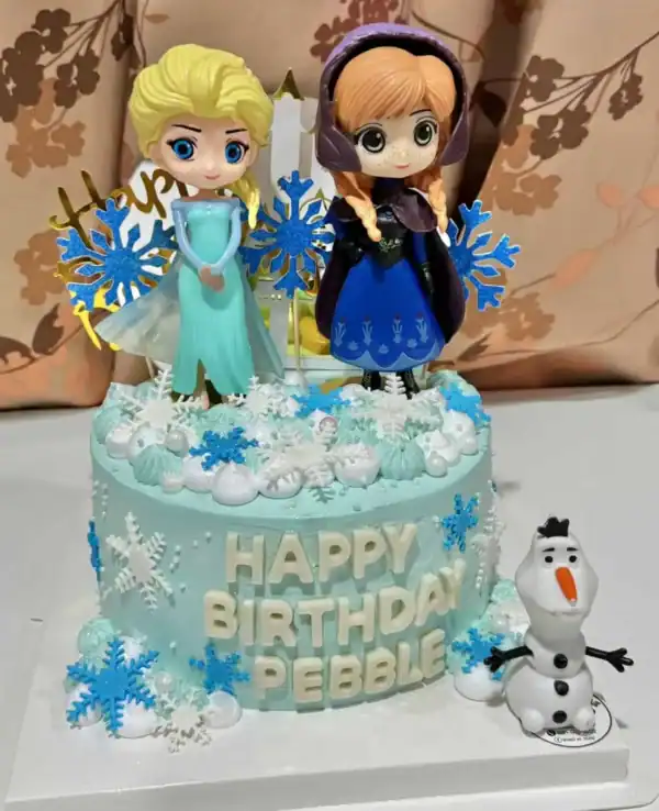 ประกอบด้วยตัวละครการ์ตูนจากภาพยนตร์เรื่อง Frozen บนเค้กสีฟ้าสีขาวพร้อมรายละเอียดหิมะและลูกบอลน้ำแข็งสำหรับฉลองวันเกิดเด็กผู้หญิง.