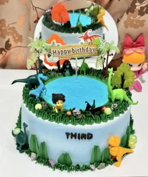 เค้กไดโนเสาร์สีสันสดใสพร้อมตัวการ์ตูนไดโนเสาร์และฉากน้ำพุในงานเลี้ยงวันเกิดเด็ก ๆ.