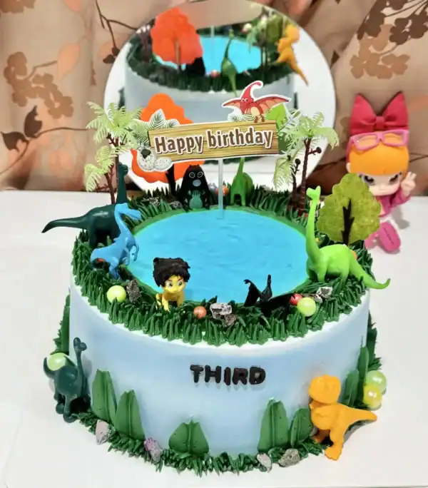 เค้กไดโนเสาร์สีสันสดใสพร้อมตัวการ์ตูนไดโนเสาร์และฉากน้ำพุในงานเลี้ยงวันเกิดเด็ก ๆ.