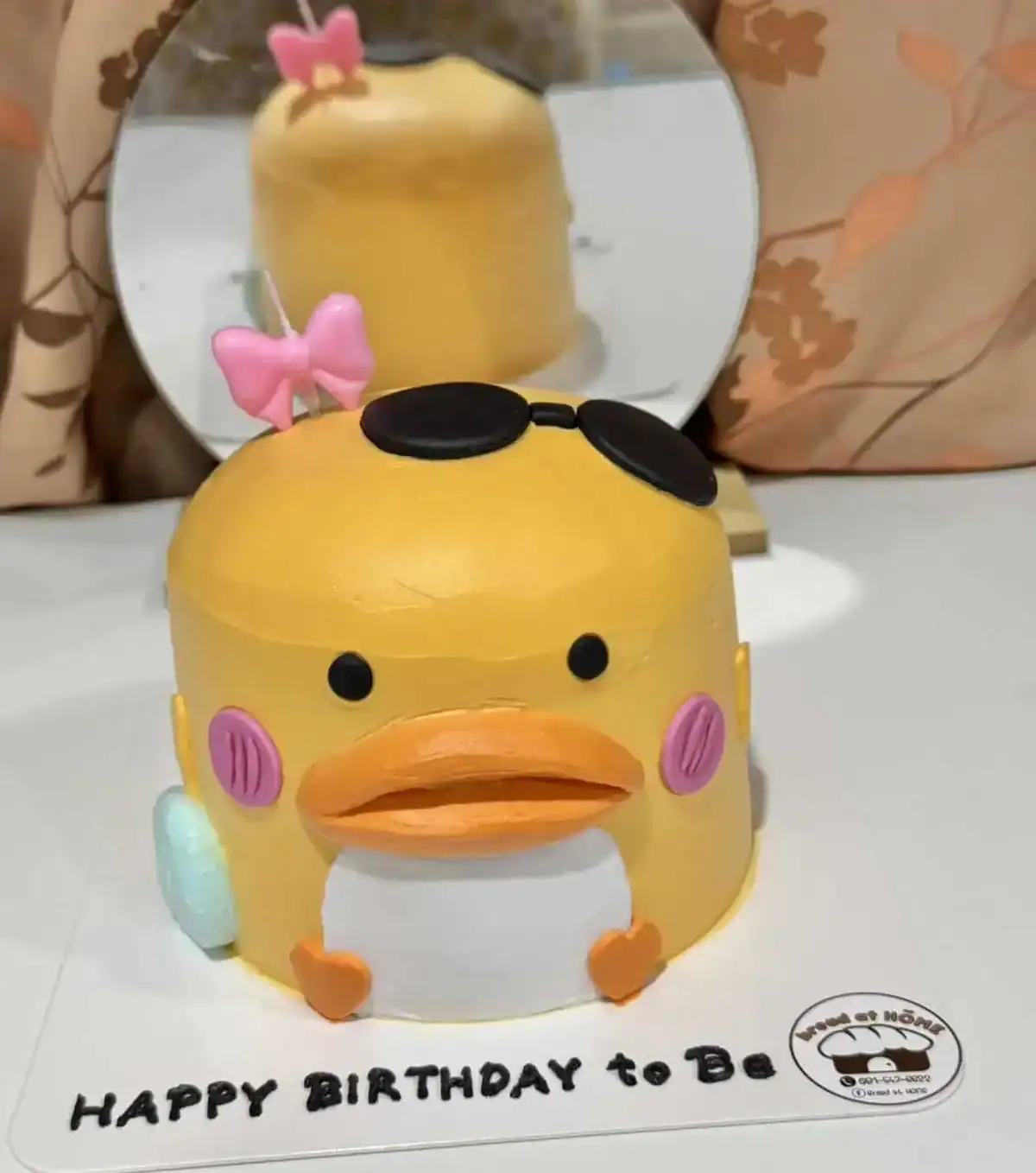 เค้กเป็ดน้อย 3 มิติสุดน่ารัก พร้อมแต่งด้วยแว่นตาและโบว์สีชมพู เหมาะสำหรับฉลองวันเกิดและโมเมนต์พิเศษต่าง ๆ.