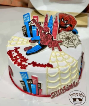เค้กสไปเดอร์แมนสุดน่ารักพร้อมดีไซน์เมืองและใยแมงมุม เหมาะสำหรับงานปาร์ตี้เด็กที่ชื่นชอบฮีโร่สไปเดอร์แมนและการผจญภัยในโลกของซูเปอร์ฮีโร่.