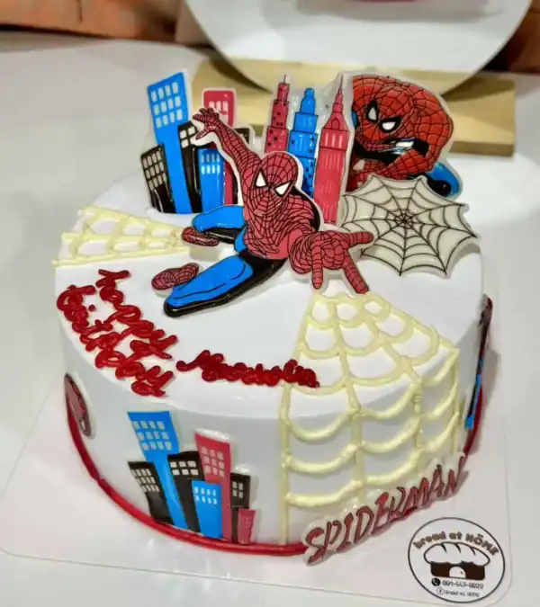 เค้กสไปเดอร์แมนสุดน่ารักพร้อมดีไซน์เมืองและใยแมงมุม เหมาะสำหรับงานปาร์ตี้เด็กที่ชื่นชอบฮีโร่สไปเดอร์แมนและการผจญภัยในโลกของซูเปอร์ฮีโร่.