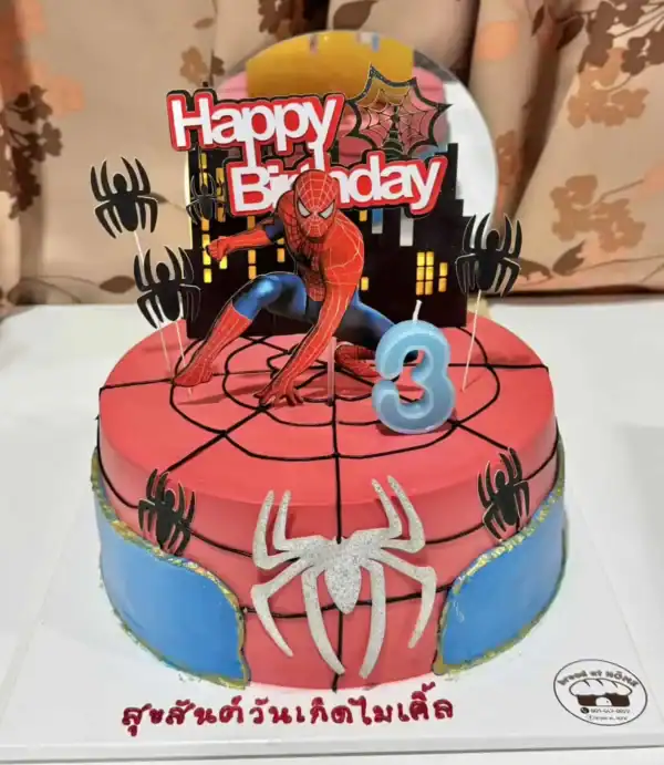 เค้กสไปเดอร์แมนหลากสีสันบนโต๊ะ พร้อมการตกแต่งด้วยแมงมุมและคาแรคเตอร์ Spiderman สำหรับงานวันเกิดเด็กอายุ 3 ปี.
