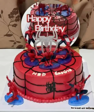 เค้กวันเกิดสไปเดอร์แมนพร้อมของตกแต่งและเทียน รูปการ์ตูนซูเปอร์ฮีโร่สำหรับงานปาร์ตี้เด็กๆ สื่อถึงความสนุกและความน่ารักของธีมซูเปอร์ฮีโร่ในวันเกิด.