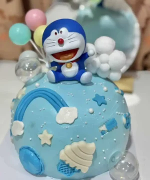 เทียนเค้กวันเกิดสีฟ้าพร้อมของตกแต่งรูปการ์ตูนโดราเอม่อนและท้องฟ้าในธีมสายรุ้งและก้อนเมฆ สร้างบรรยากาศสนุกสนานในงานปาร์ตี้วันเกิดของเด็กๆ.